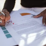 Hands editing a printed draft with notes and highlights